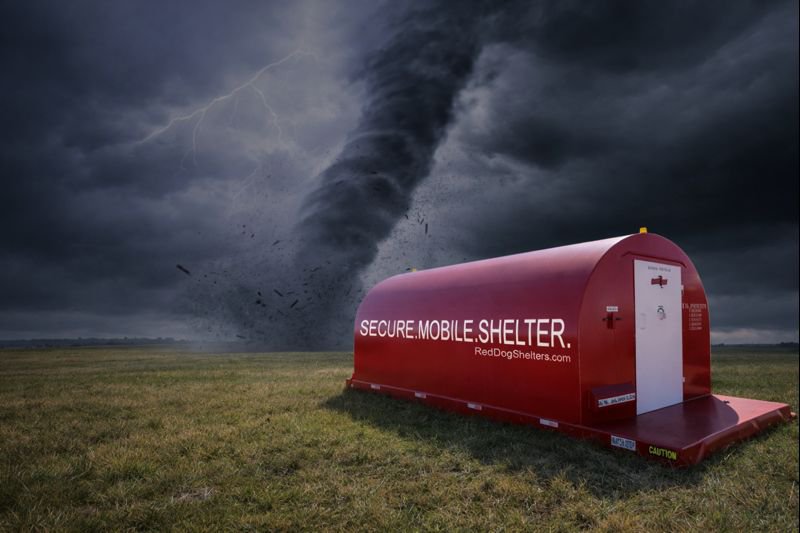 A composite image featuring a red Red Dog mobile storm shelter positioned in a grassy field, with a large, destructive tornado and lightning striking in the background under a dark, stormy sky.